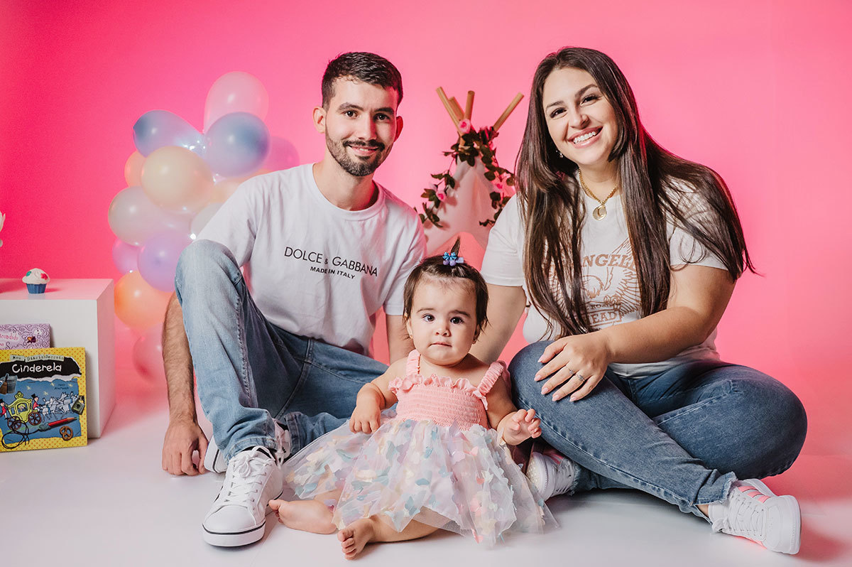 Foto de 1 aninho da Lara com o papai e a mamãe em estudio com decoração colorida