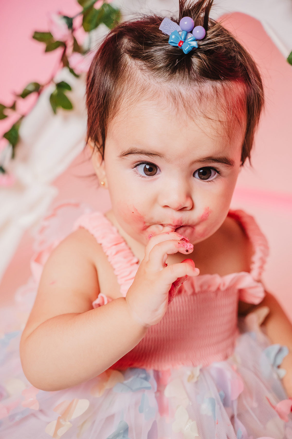 A criança com o dedo na boca, saboreando um bolinho
