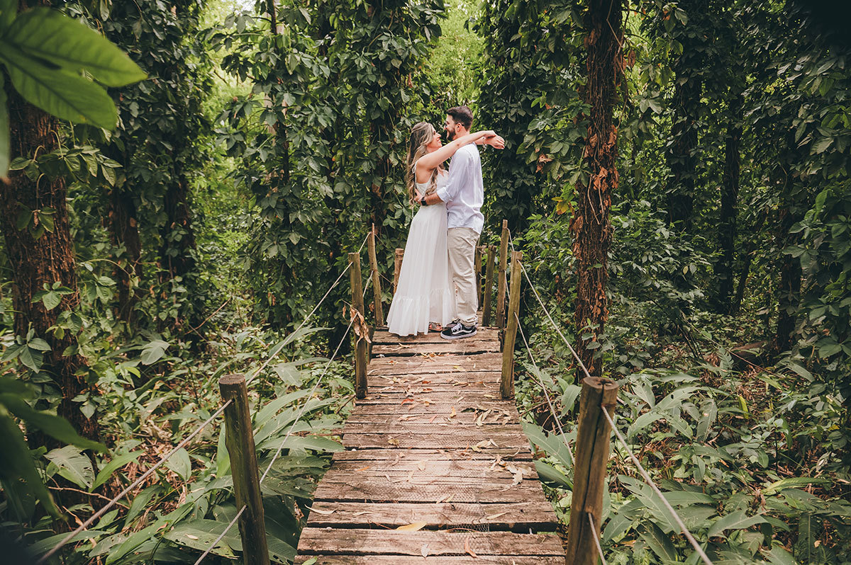 Foto do casal em cima de uma ponte de madeira