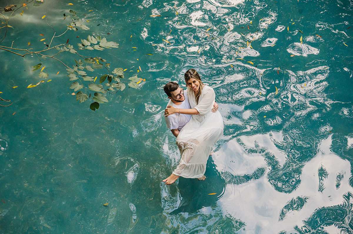 Noivos brincando dentro da piscna, noiva no colo do noivo