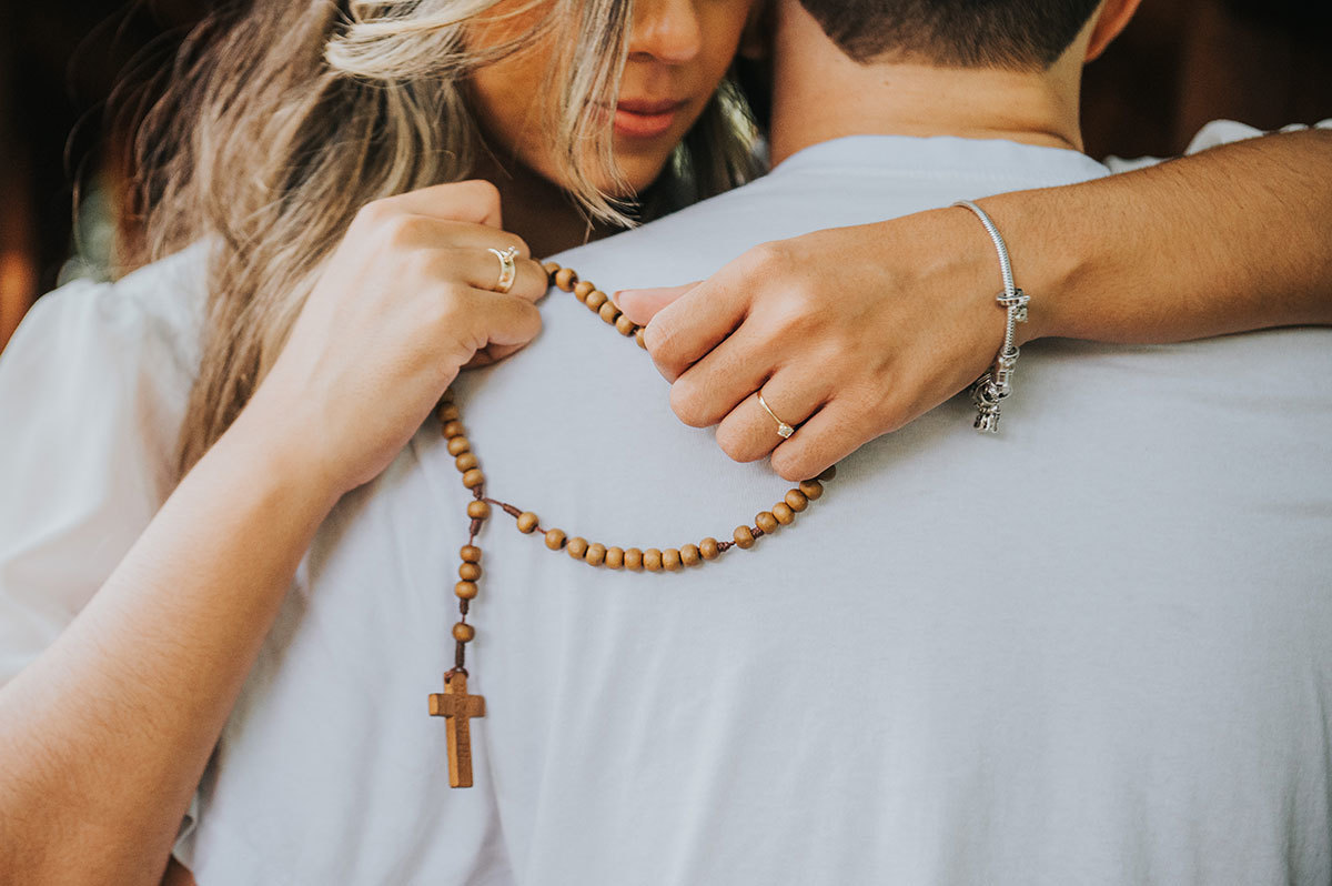 Noiva abraçada ao noivo, com o rosário