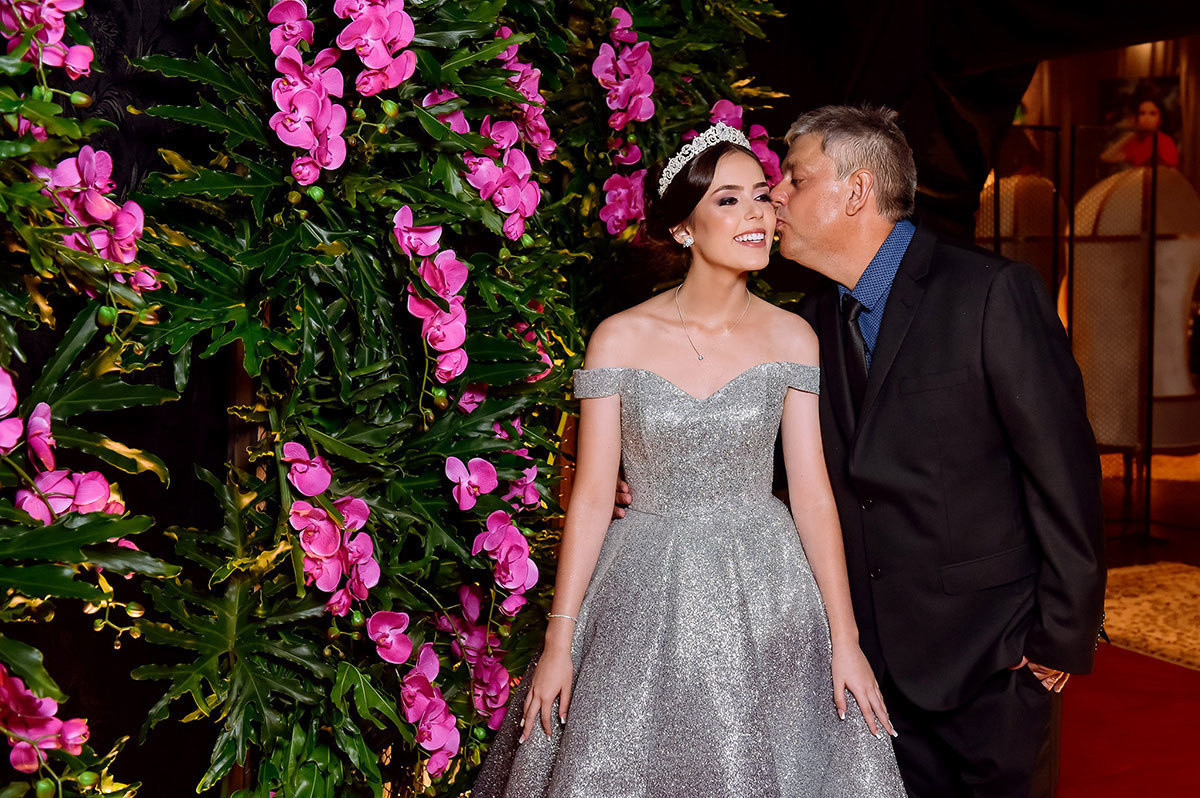 Momento de carinho, o pai beijando o rosto da debutante