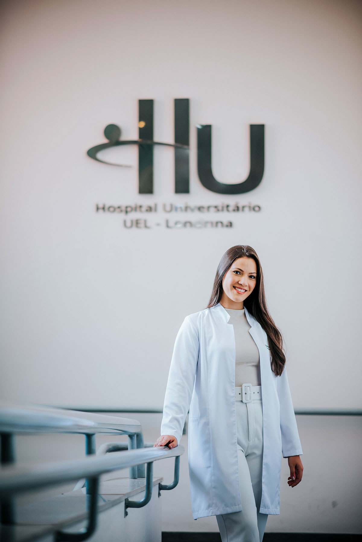 Foto da formanda em frente ao letreiro do Hospital Universitário de Londrina