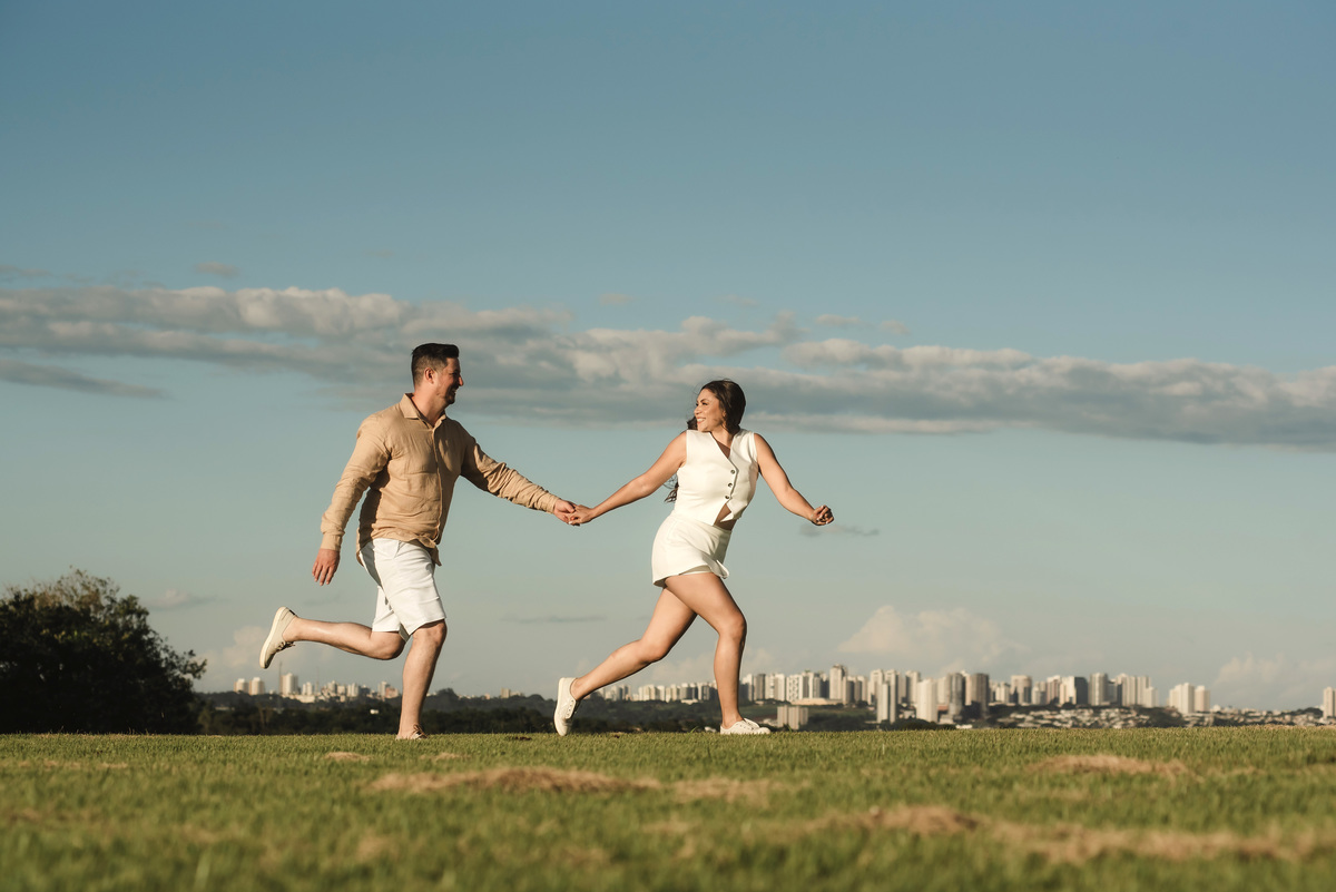 Casal correndo de mãos dadas em ensaio pré-wedding ao ar livre