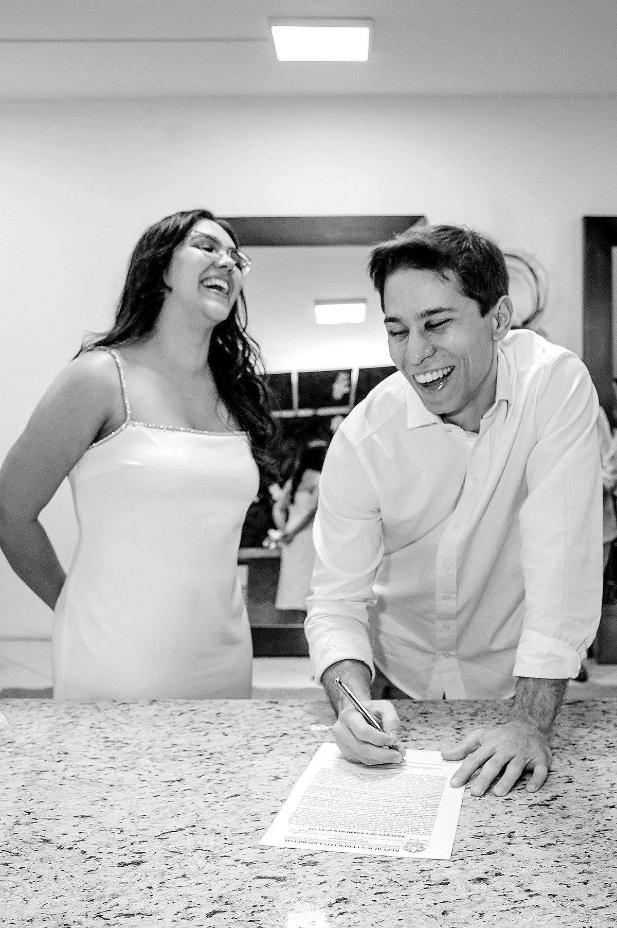 Noivos dando risada enquanto assinam
