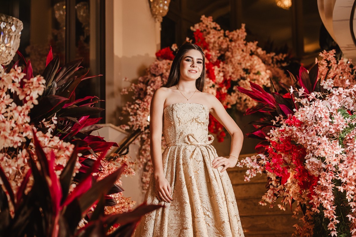 Debutante na escadaria com muitas flores em volta
