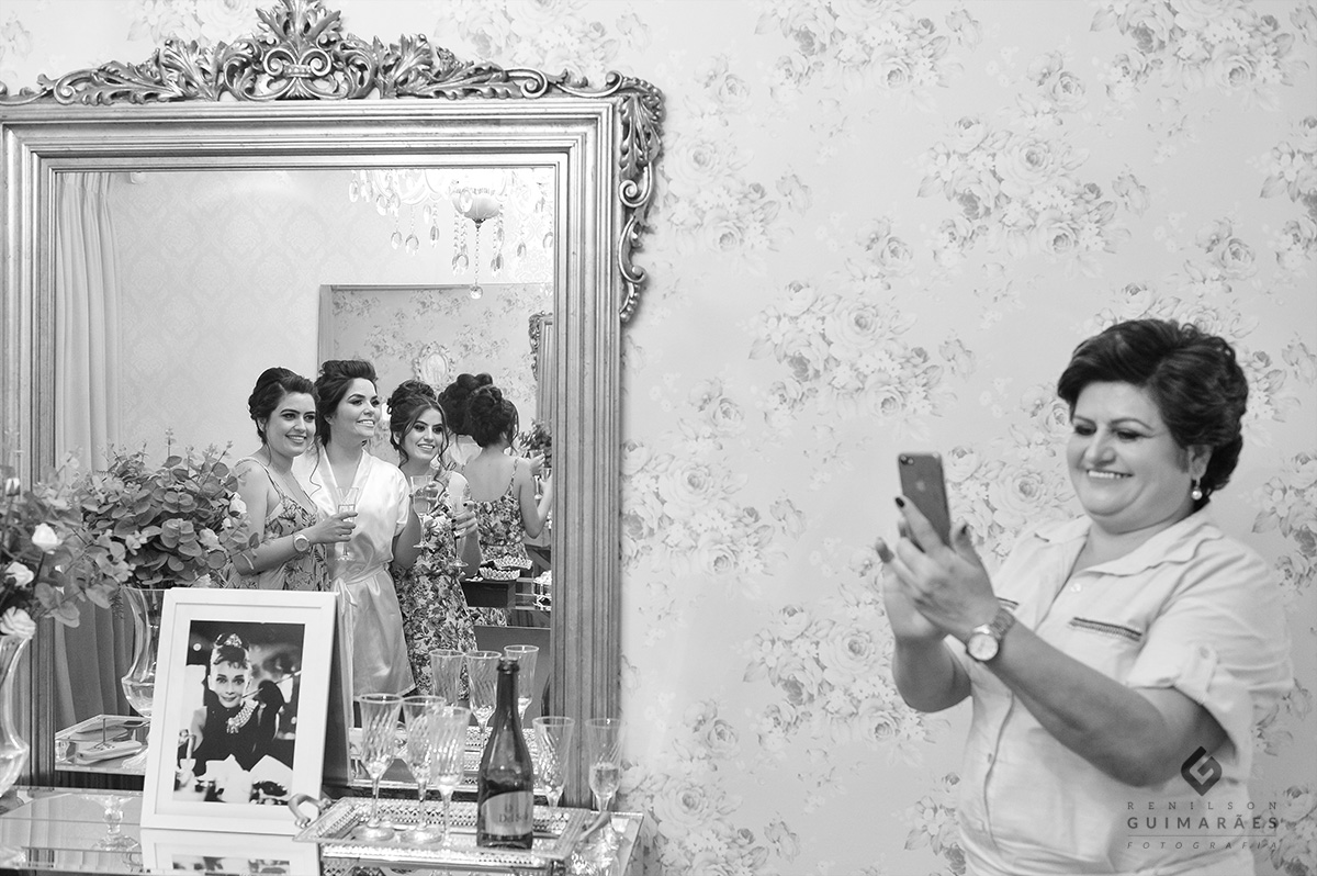 a mãe da noiva tirando fotos das três filhas juntas,