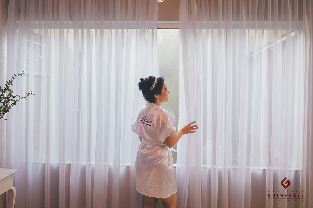 A noiva olhando pela janela pra ver como estava o tempo