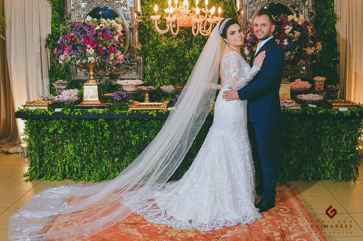 Noivos na frente da mesa de doces