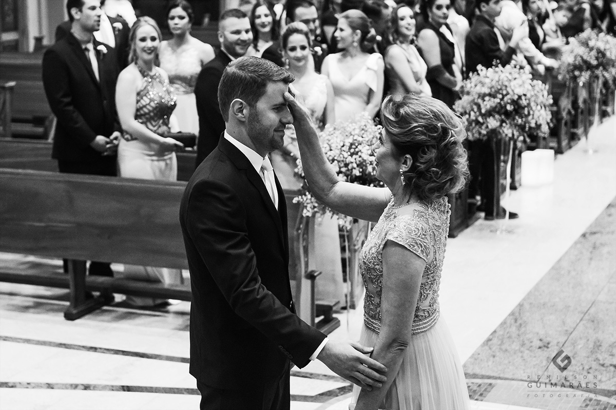 a mãe do noivo fazendo o sinal da cruz nele