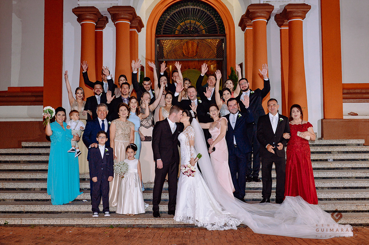 Foto dos padrinhos com os noivos na escadaria da igreja