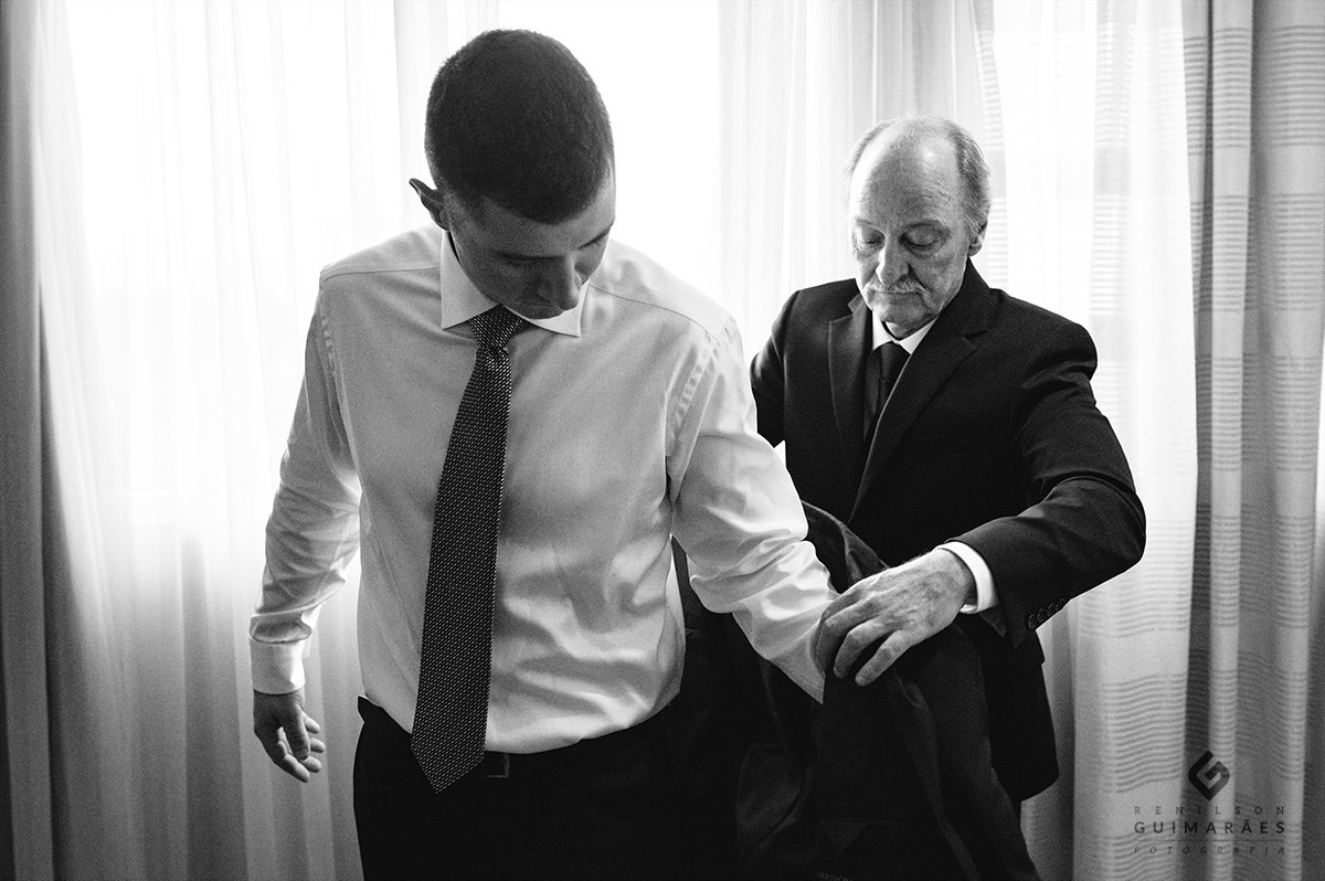 pai do noivo colocando o paletó nele