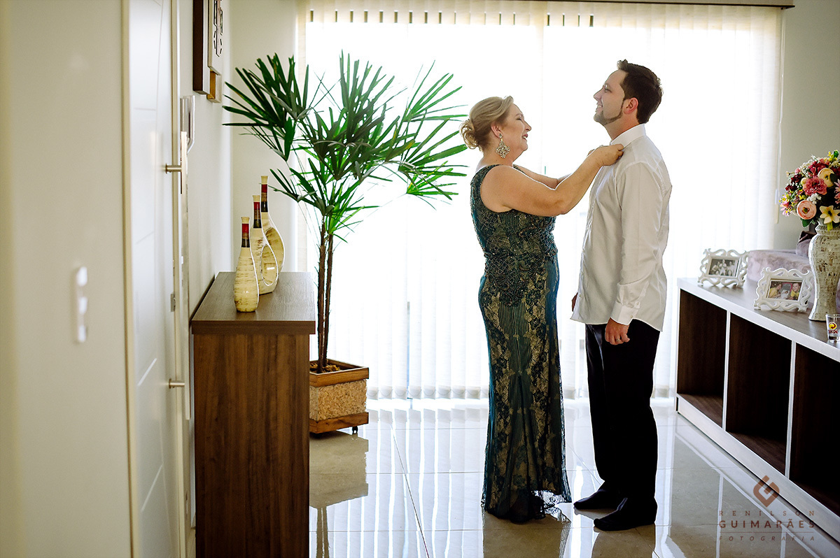 A mãe do noivo ajudando ele a se arrumar