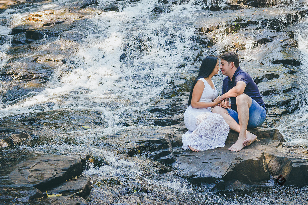 Casal sentado nas pedras da cachoeira