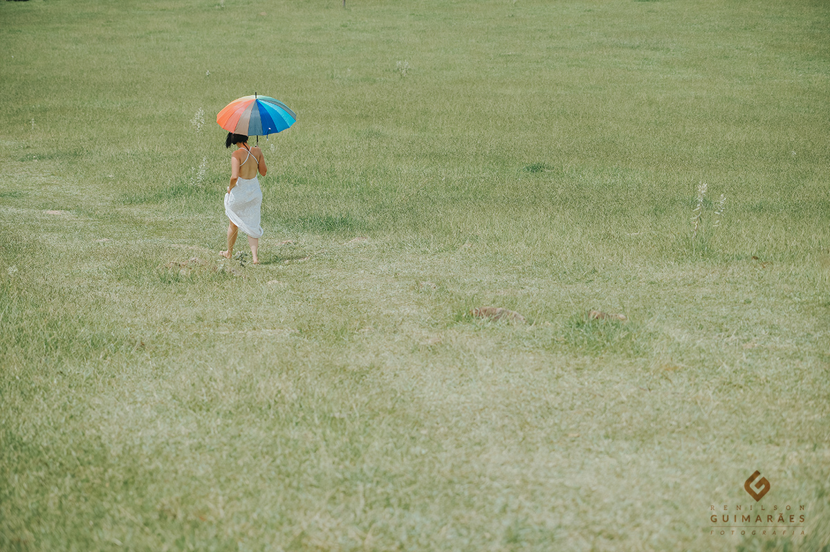 A noiva andando na grama com a sombrinha