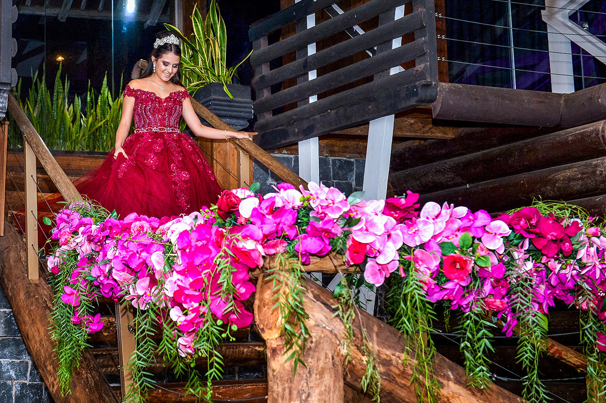 A aniversariante descendo as escadas decoradas com flores