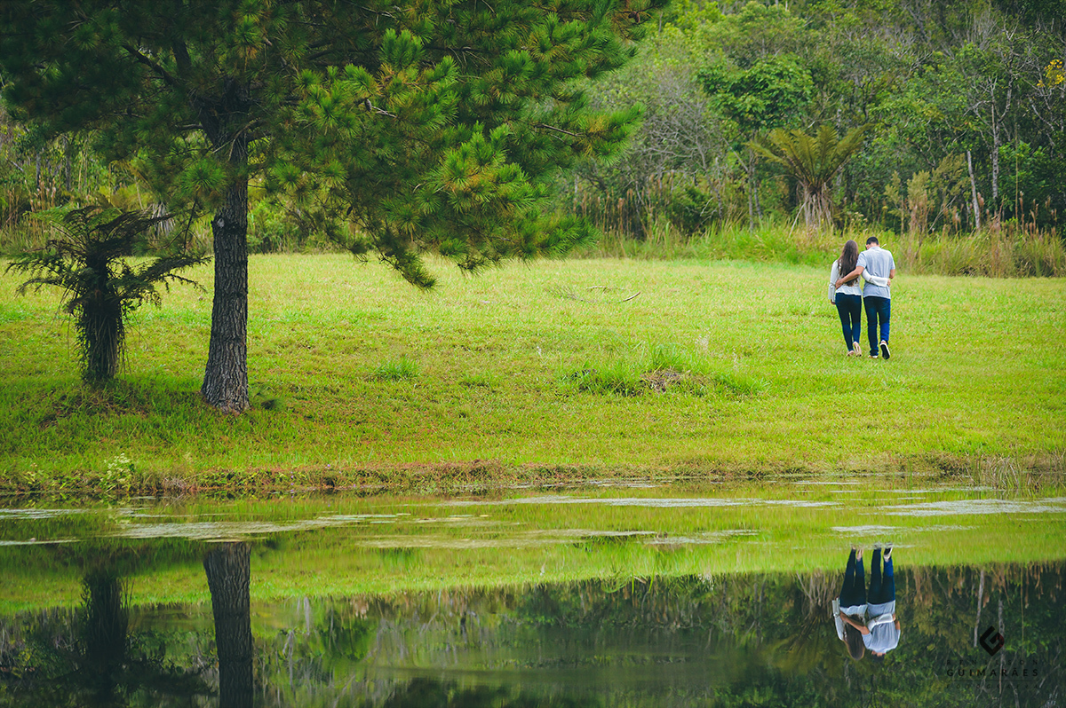 Noivos abraçados de costas para o lago