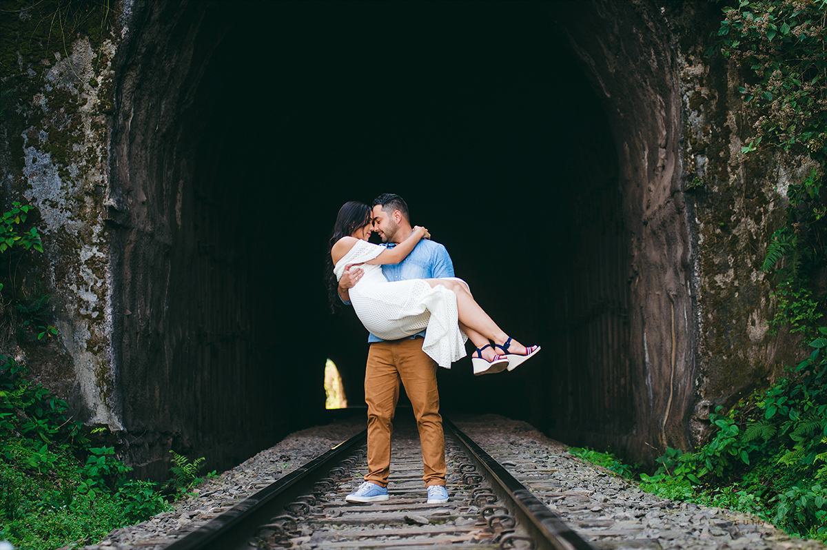 Noivo pegando a noiva no colo na linha de trem