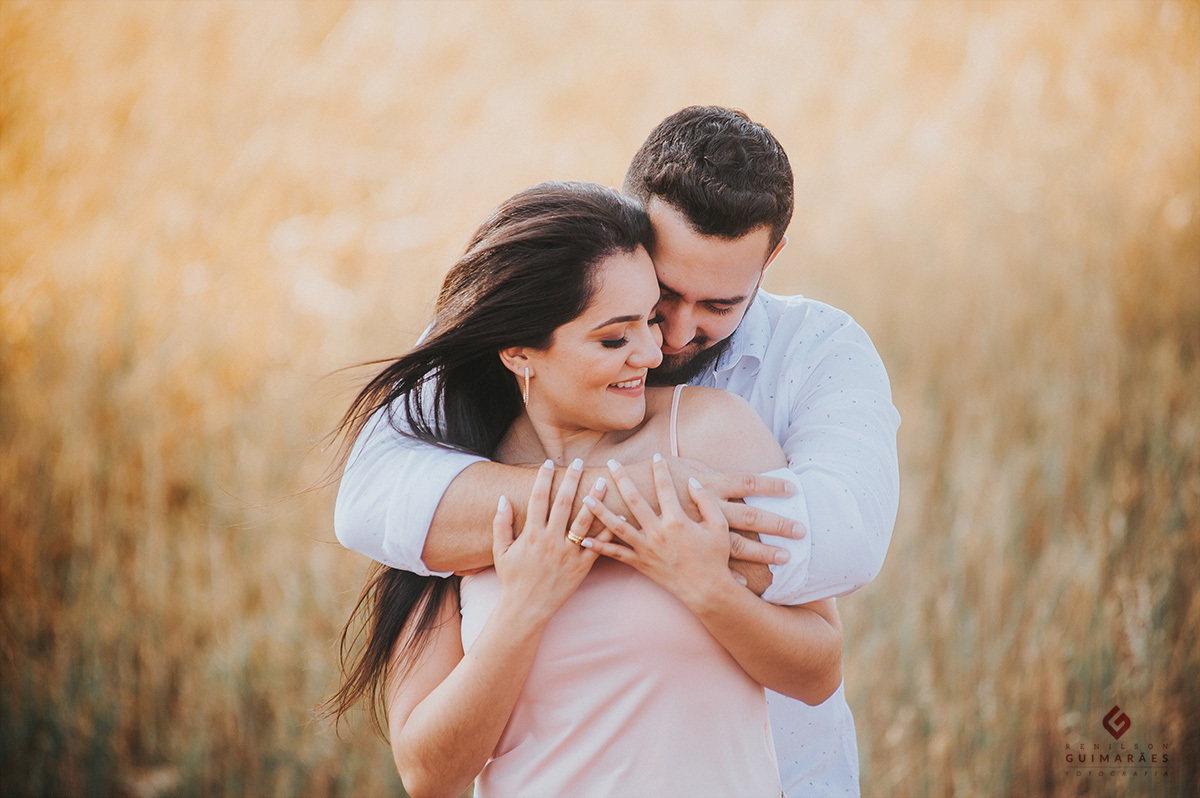 Noivos abraçados e ao fundo uma plantação de trigo
