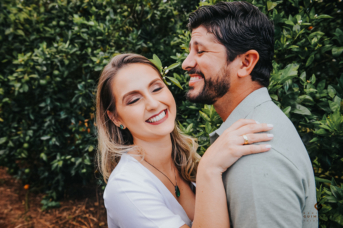 Casal de noivos sorrindo na plantação de laranjas