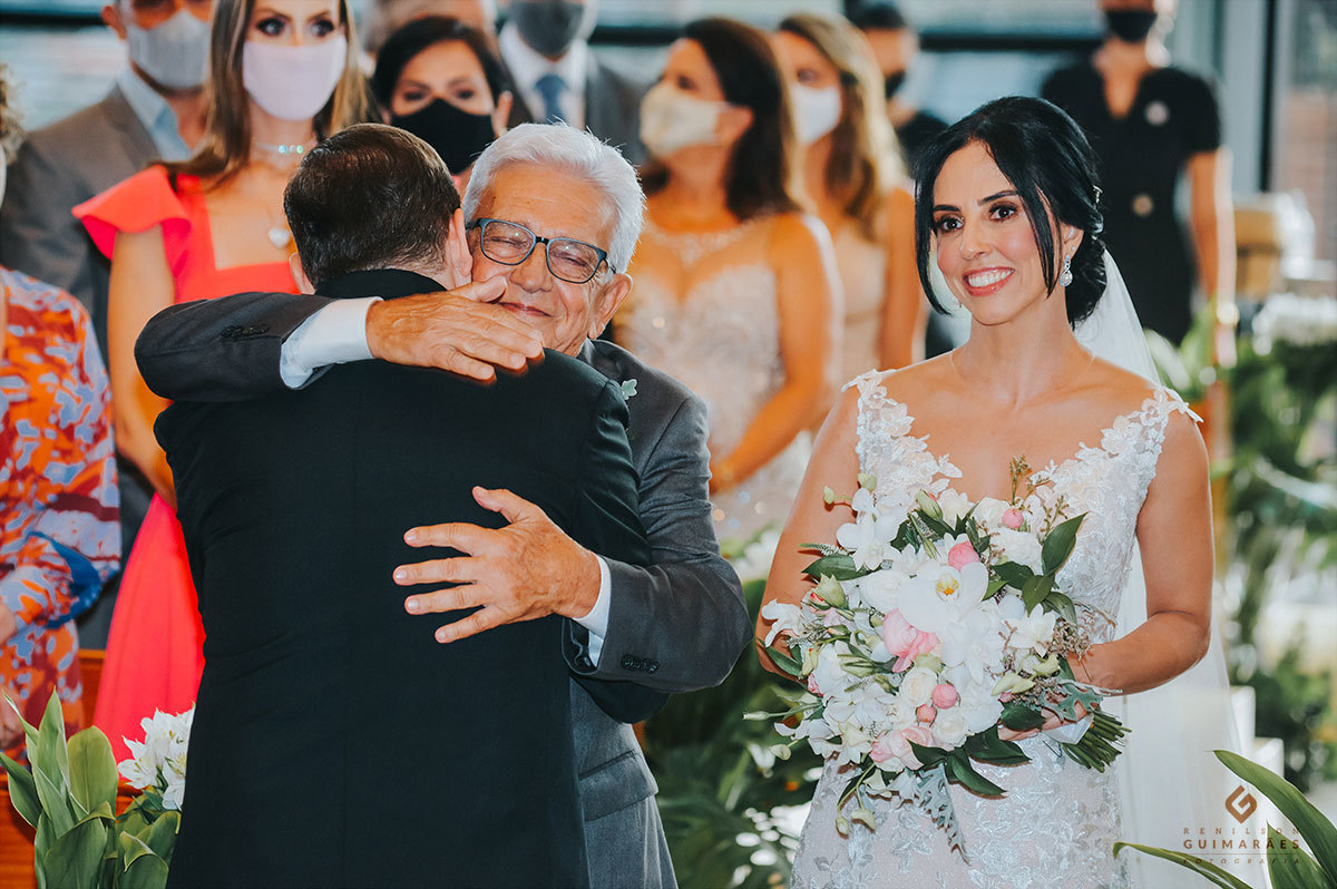 O pai da noiva abraçando o noivo emocionado com um grande sorriso