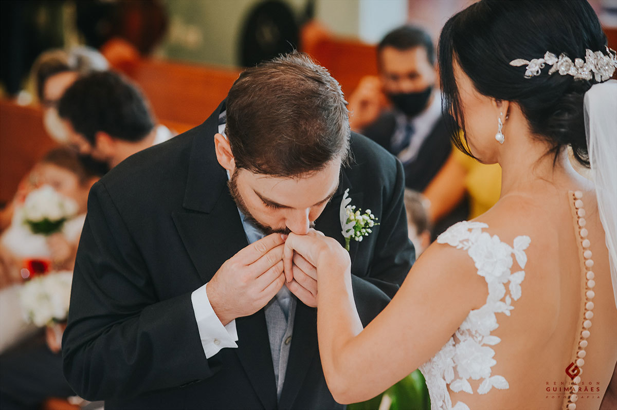 O noivo beijando a mão da noiva após colocar as alianças