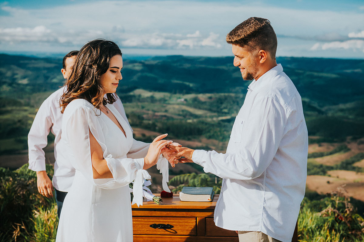 A noiva colocando a aliança no noivo