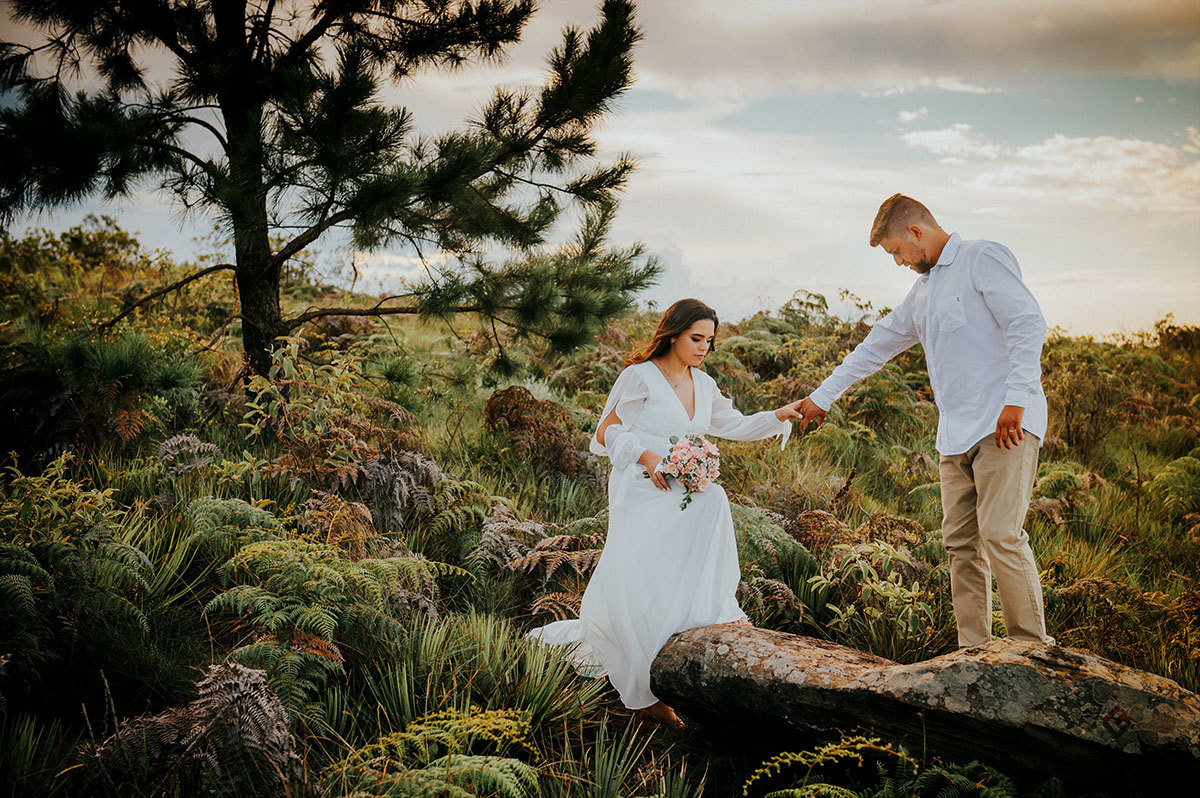 Noivo ajudando a noiva a subir na pedra