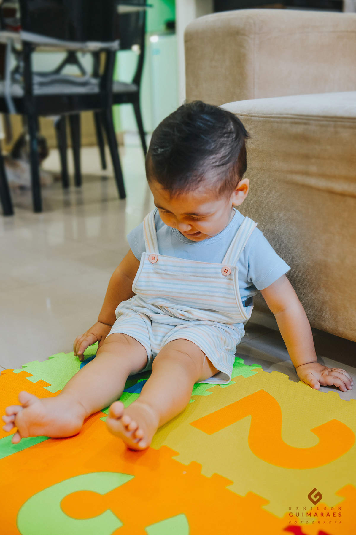 O Pedro dando risada sentado no chão da sala