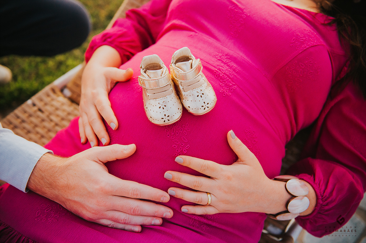 Sapatinhos do bebê em cima da barriga