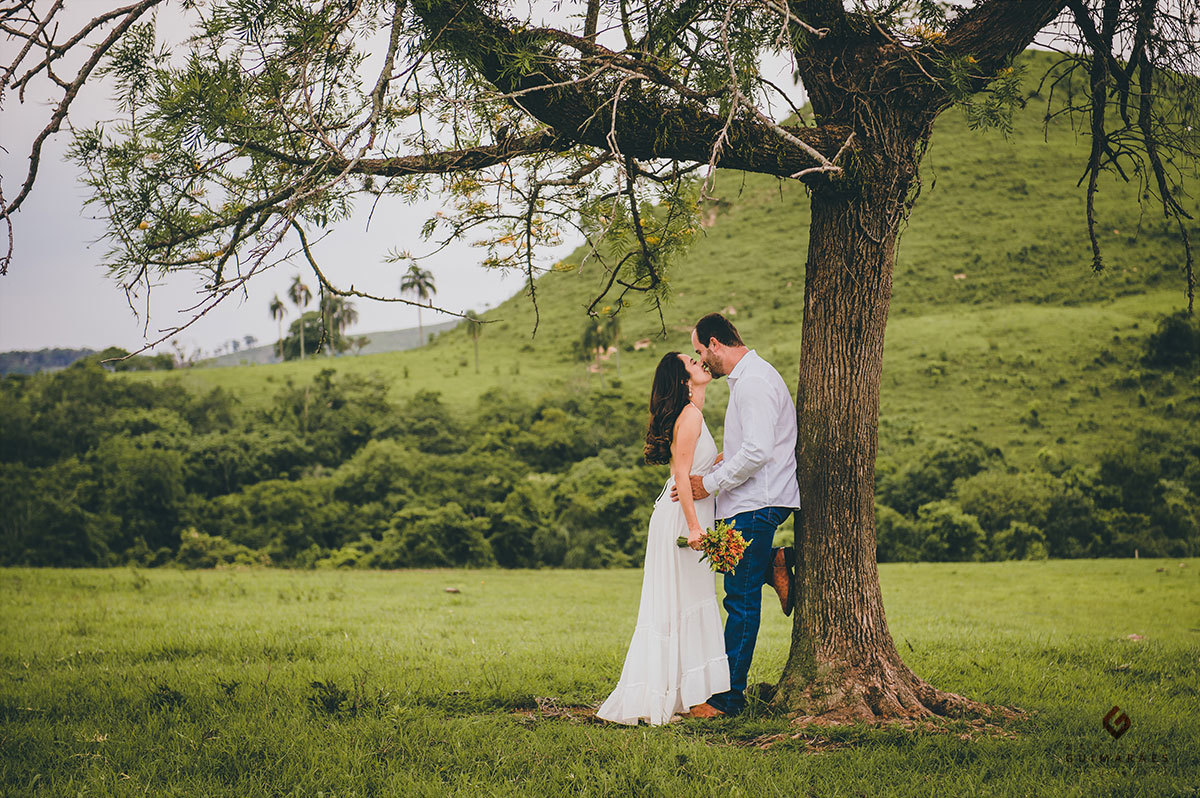 Noivo encostado na árvore abraçado a noiva