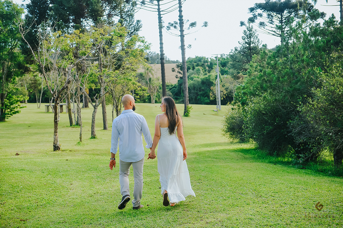 Foto dos noivos de costas andando no recanto pinhão