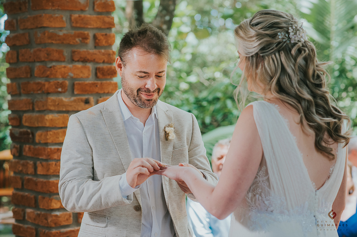 O noivo colocando a aliança na mão da noiva