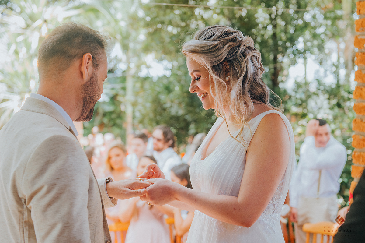 A noiva colocando a aliança no noivo