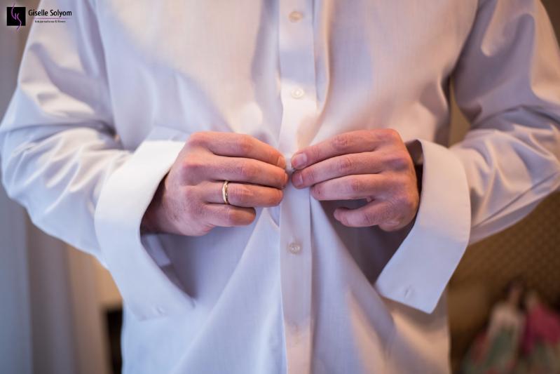 Foto de Giselle Solyom, fotógrafa de Casamento,  mostra as mãos do noivo abotoando a camisa enquanto se prepara no Hotel Bourbon Curitiba no making of.
