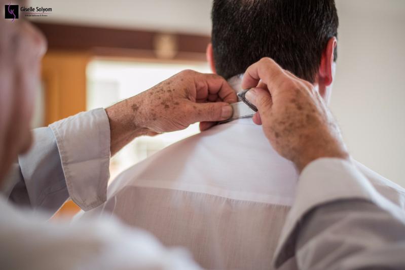 As mãos do pai do noivo abotoando a camisa enquanto se prepara em suíte do Hotel Bourbon Curitiba no making of feito por Giselle Solyom, fotógrafa de Casamento com suas lentes especiais.