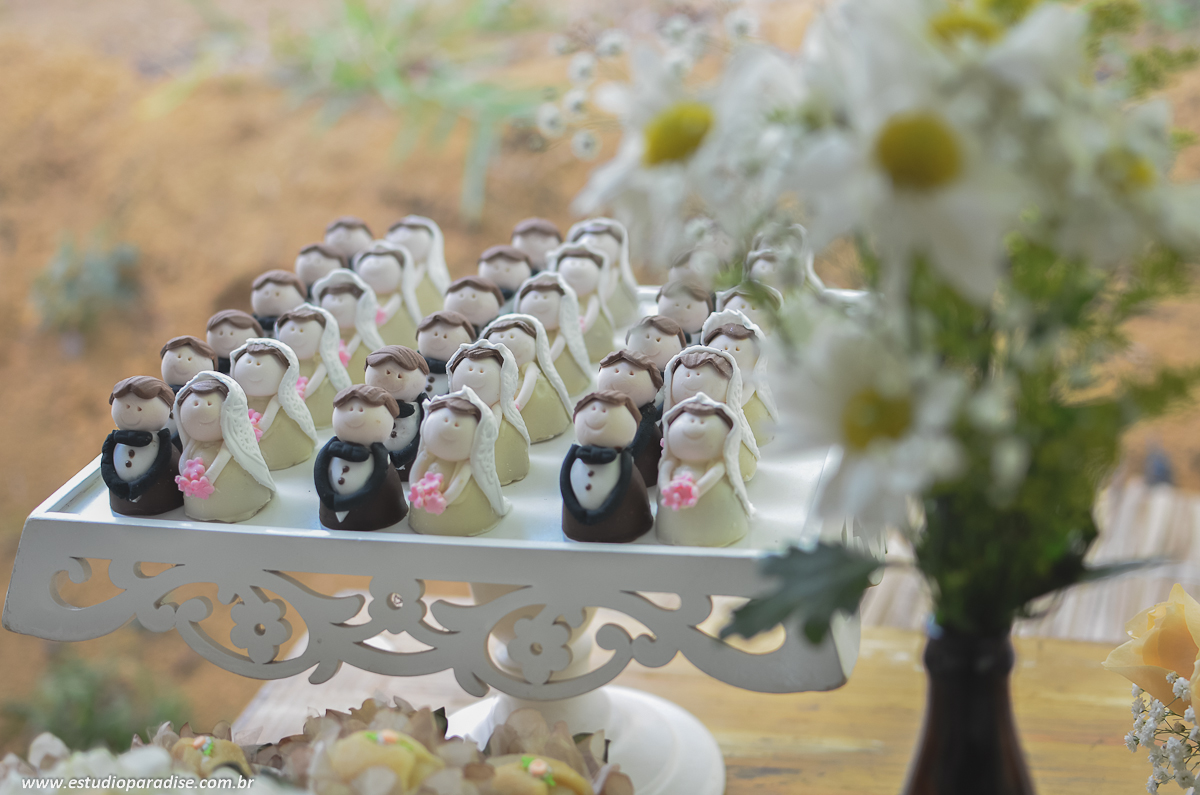 Decoração e docinhos da mesa do bolo na recepção do casamento ao ar livre de dia em Chácara Minas Gerais