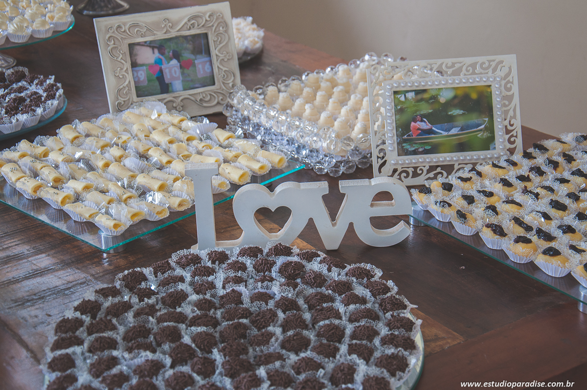 Decoração da mesa do bolo com docinhos e porta retratos com fotos do e-session do casal