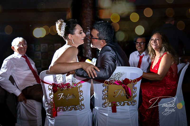 casal sentado na mesa especial detalhe na cadeira par perfeito pais ao fundo jantar decoração casamento celebração terra nova itauba matupá sinop sorriso guaranta  mato grosso fotografia criativa dominik capela lago de matupa