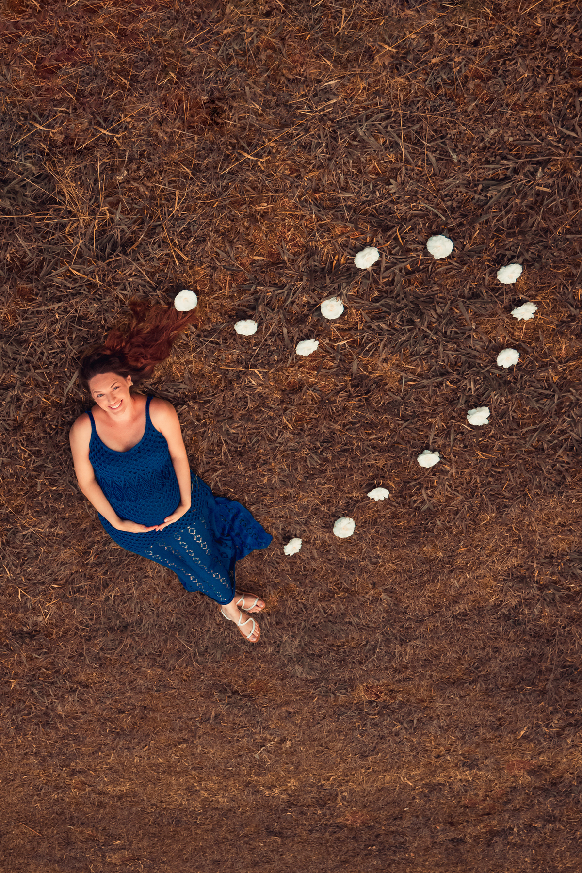 gestante deitada no chão com pedras em volta formando um coração por rafael maia