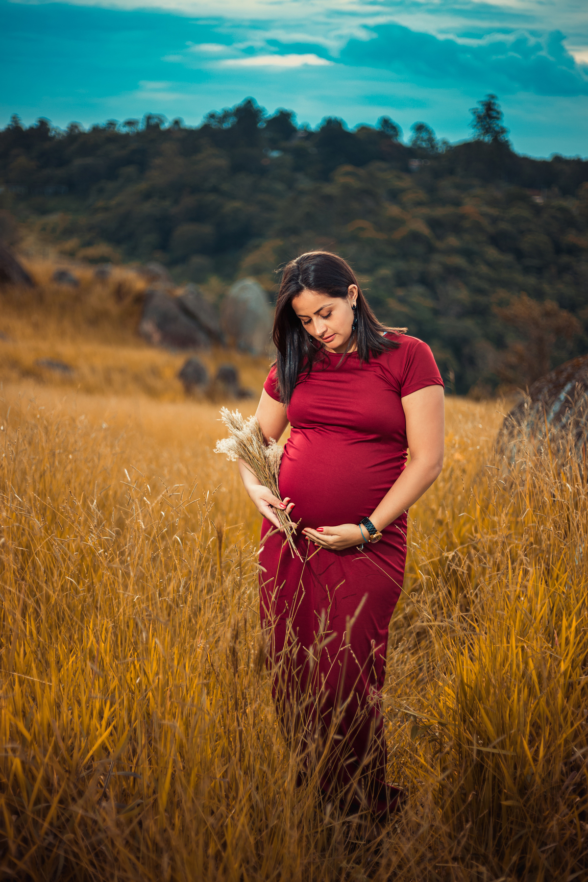 mulher com um vestido vermelho e folhagens na mão em ensaio gestante