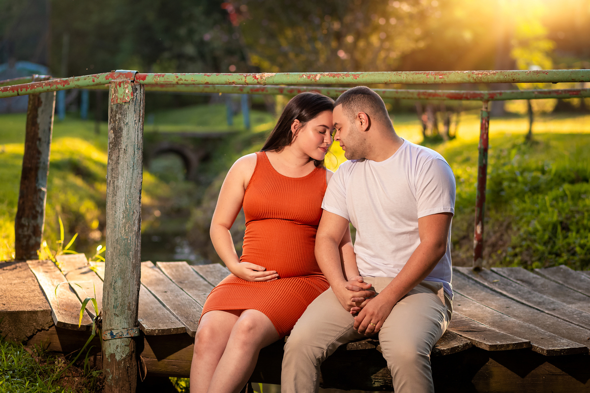 ensaio gestante com marido se olhando sentados na ponte realizado no roque raquete em são roque sp