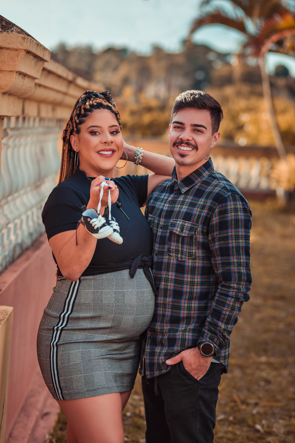 casal segurando o sapato do bebe em um ensaio gestante na estação ferroviária 