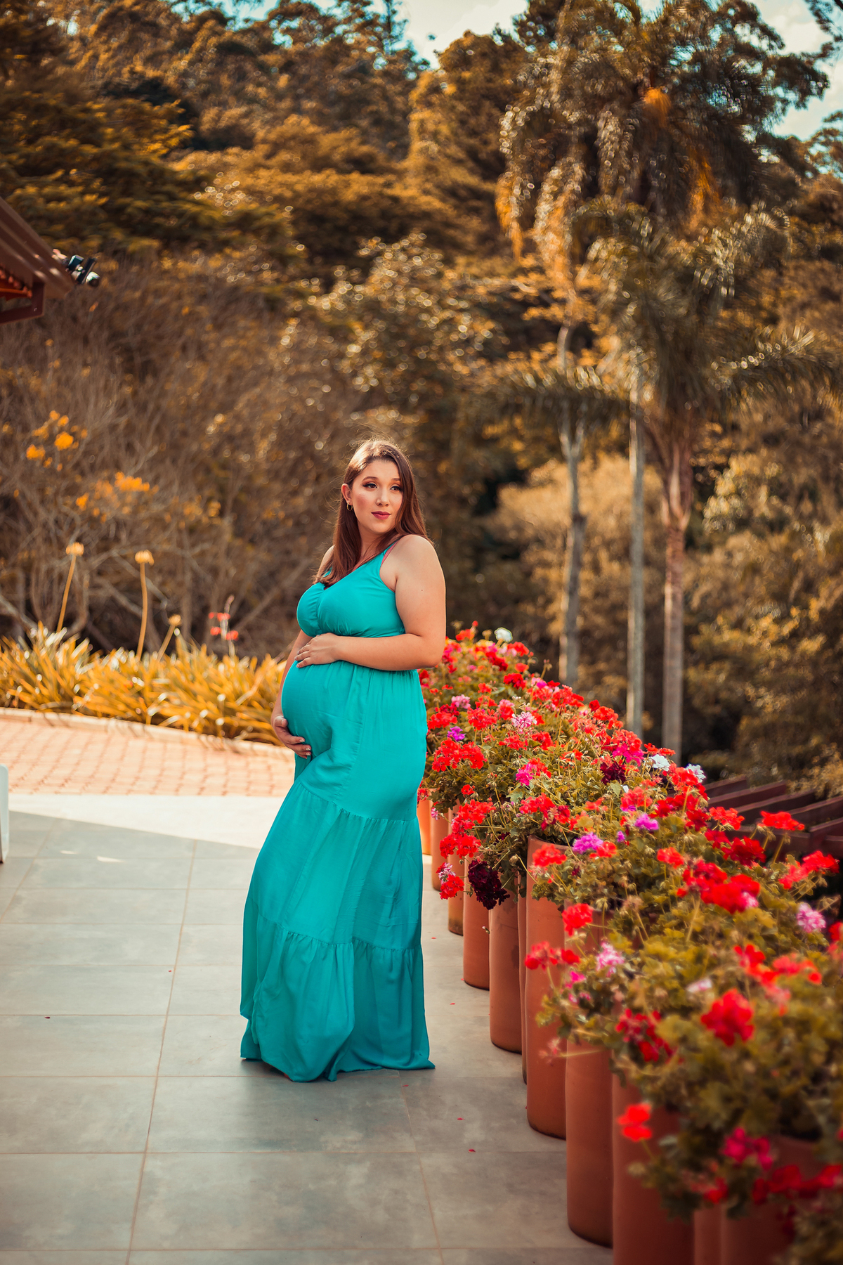 moça com um vestido azul em um ambiente floral em ensaio de gestante por rafael maia