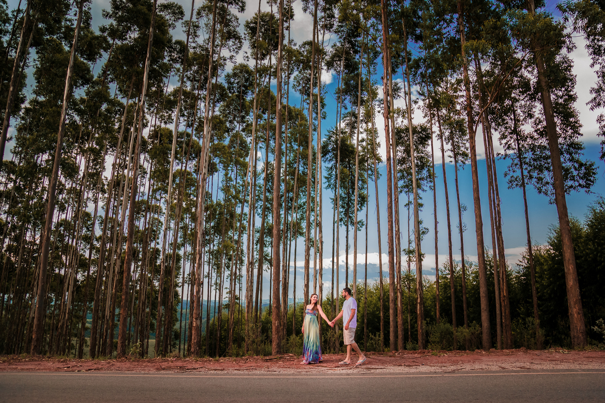 gestante com o marido em ensaio em sao roque no meio das arvores na estrada em mairinque sp