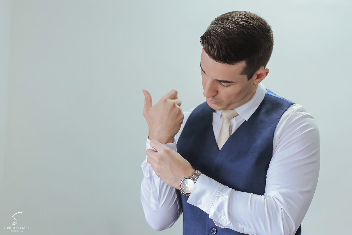 Lindo retrato do noivo abotoando o punho da camisa em casamento em Uberlândia 