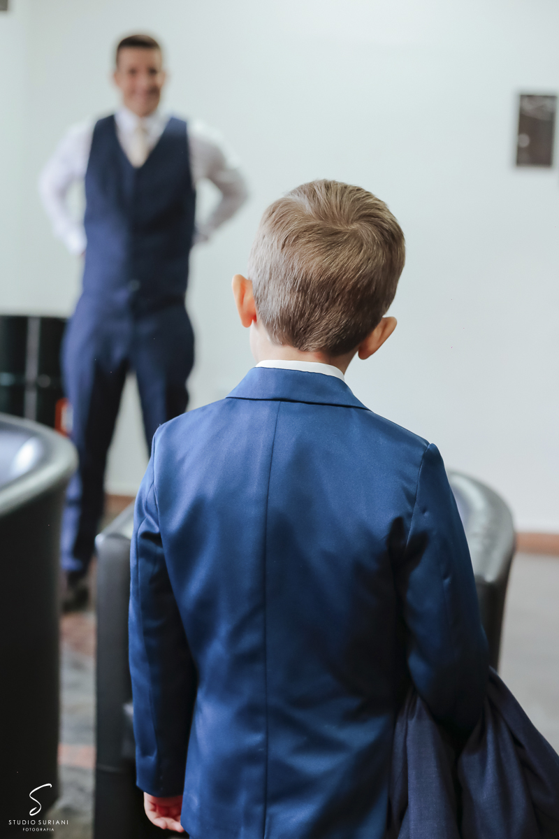 Filho olhando o pai se arrumar para casamento com a mãe 