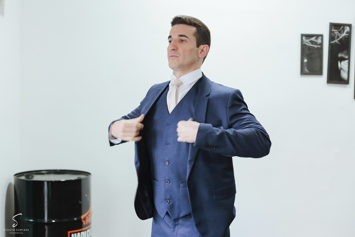 Noivo colocando o terno no salão 