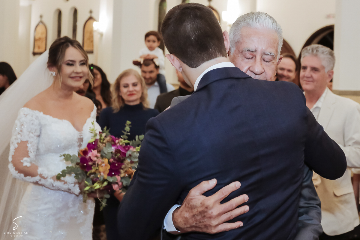 Abraço do noivo com o pai da noiva e noiva emocionada 