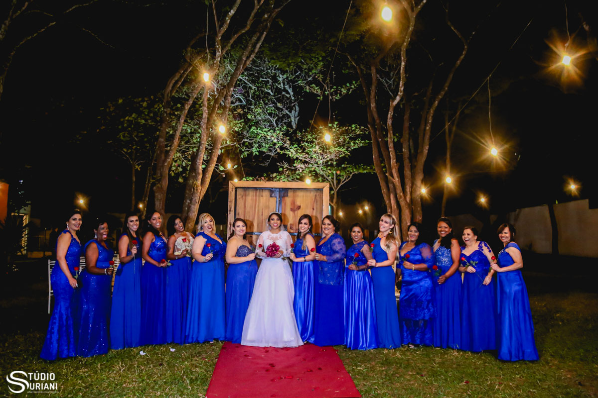 madrinhas de azul e buque vermelho em casamento ao ar livre com iluminação de lampadas amarelas